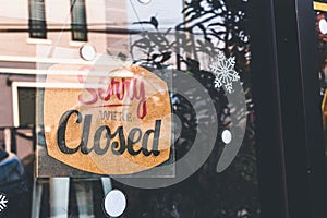 Sorry we're closed sign. grunge image hanging on a dirty glass door
