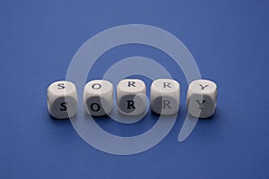 Sorry word on wooden cubes, clasic blue background, copy space. Apology message photo