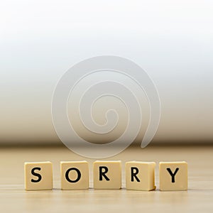 Sorry word written in  cube on wooden floor on white background