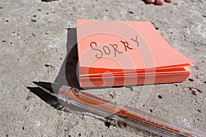 sorry written on an orange sticker and pen on concrete surface