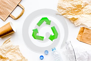 Sorting waste and recycle. Green paper recycling sign among waste paper, plastic, glass, polyethylene on white