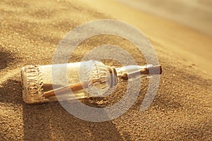 SOS message in glass bottle on sand