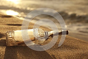 SOS message in glass bottle on sand near sea