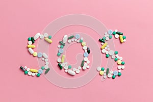 SOS sign made of pills and capsules on a pink background. The concept of illness and drug addiction. Suicide. Death from