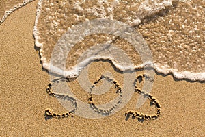 SOS - word drawn on the sand beach