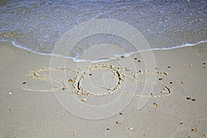 SOS - word drawn on the sand beach with the soft wave.