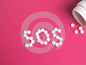 SOS word made of pills and capsules on a pink background. Pills on a blue background. Word sos.