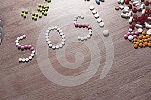 SOS word made of pills on a wooden table. Different pills and blister packs