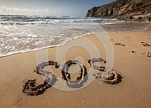 SOS written in the sand on a beach