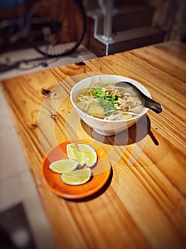 Soto ayam, a typical Indonesian breakfast.  smells of spices and turmeric.  topped with lime. Make it tastier.