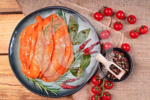 Sottilissime raw chicken fillet.Chicken fillet thinly sliced, sottilissime in red marinade on a plate with vegetables on a wooden photo