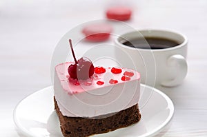 Souffle cake in the form of heart with cup of coffe and macaroons on a wooden table