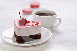 Souffle cake in the form of heart  with cup of coffee and macaroons on wooden table