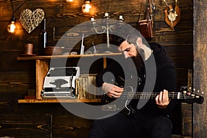 Soul music. Man bearded musician enjoy evening with bass guitar, wooden background. Man with beard holds black electric