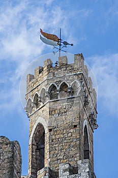 Ancient bell tower with bells and flag of the historic city