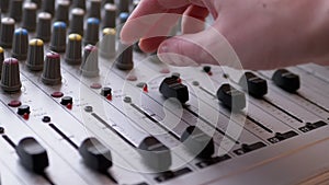 Sound engineer, dj moves sliders with fingers on audio mixer in recording studio