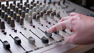 Sound engineer, dj moves sliders with fingers on audio mixer in recording studio