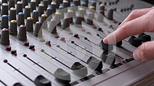 Sound engineer, dj moves sliders with fingers on audio mixer in recording studio