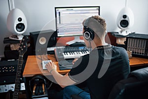 Sound engineer in headphones working and mixing music indoors in the studio