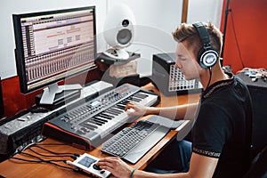 Sound engineer in headphones working and mixing music indoors in the studio