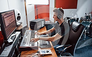 Sound engineer in headphones working and mixing music indoors in the studio