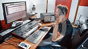 Sound engineer in headphones working and mixing music indoors in the studio