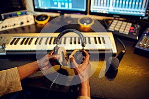 Sound engineer holds headphones, recording studio