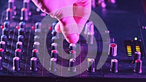 Sound Engineer Move Faders Level on Audio Mixer Console in Neon Light Close-Up