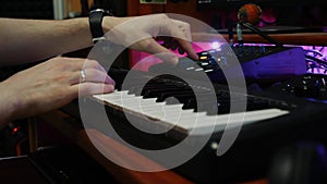 Sound engineer working at home music studio with equalizer mixing gear. Male hands playing electric piano at recording studio. Mus