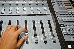 Sound engineer working on mixing console, closeup of hands doing adjust a fader