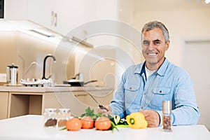 Sound mind in a sound body Smiling mature man prepares to chop the veggies to cook a vegan dish. Healthy aging concept