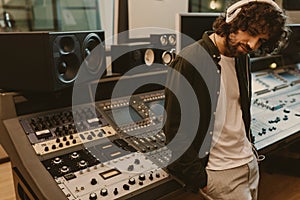 sound producer in headphones leaning back on recording equipment