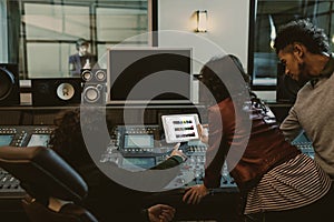 sound producers using tablet together at recording studio with youtube website