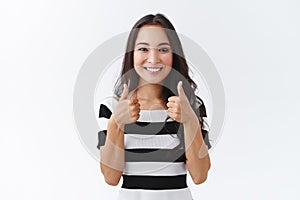 Sounds awesome. Cheerful young east-asian woman in striped t-shirt show thumbs-up and smiling, nod in agreement, give