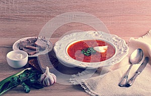 Soup in a bowl with dill, sour cream and black bread on wooden b