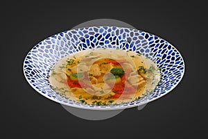 Soup consomme with vermicelli and vegetables. On a black background. Isolated