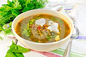 Soup lentil with spinach and feta in yellow bowl on board