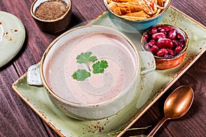 Soup with meat, olives, herbs, lemon, sour cream in bowl, black bread and spices on dark wooden background,