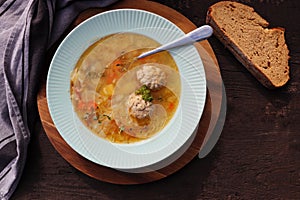 Soup with meatballs on dark background, gray linen napkin. Healthy meatball soup with vegetables. Top view