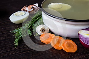 Soup with sorrel, vegetables and boiled egg, red onion, carrots, garlic, dill on dark wooden table.