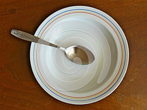 Soup Spoon in Plate On Wooden Table
