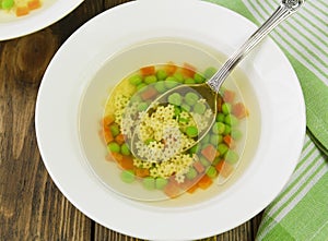 Soup with star shaped noodles, carrots and green peas
