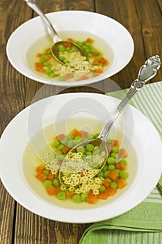 Soup with star shaped noodles, carrots and green peas