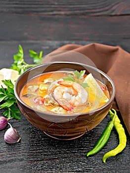 Soup Tom Yum with lemons in bowl on black wooden board