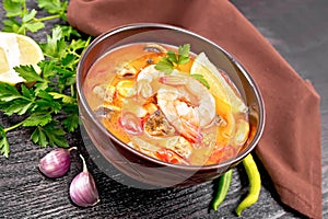 Soup Tom Yum with lemons in bowl on wooden board