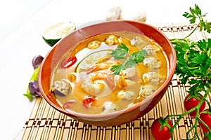 Soup Tom Yum with lime in bowl on light board