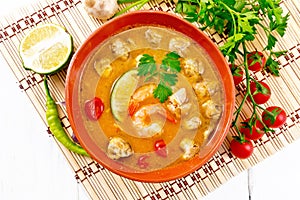 Soup Tom Yum with lime in bowl on light board top