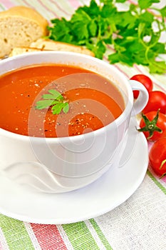 Soup tomato in bowl with tomatoes on linen napkin