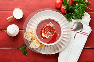 Soup. Tomato cream soup or gazpacho with herbs, seasonings, cherry tomato and parsley in white bowl on old red wooden background.