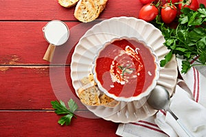 Soup. Tomato cream soup or gazpacho with herbs, seasonings, cherry tomato and parsley in white bowl on old red wooden background